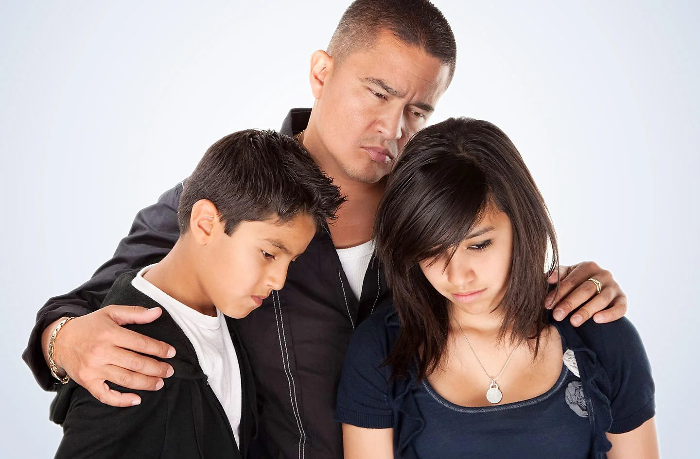 Man with hands on shoulders of a young boy and young girl.