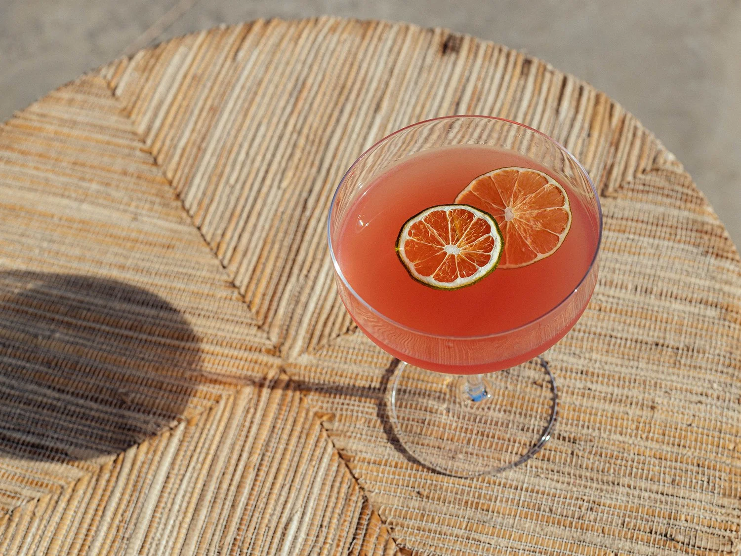 Pink craft cocktail garnished with citrus