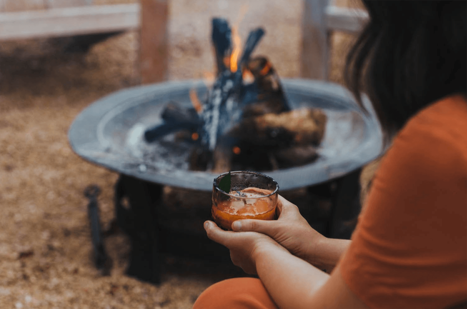 Guest enjoying a drink by a fire pit outdoors