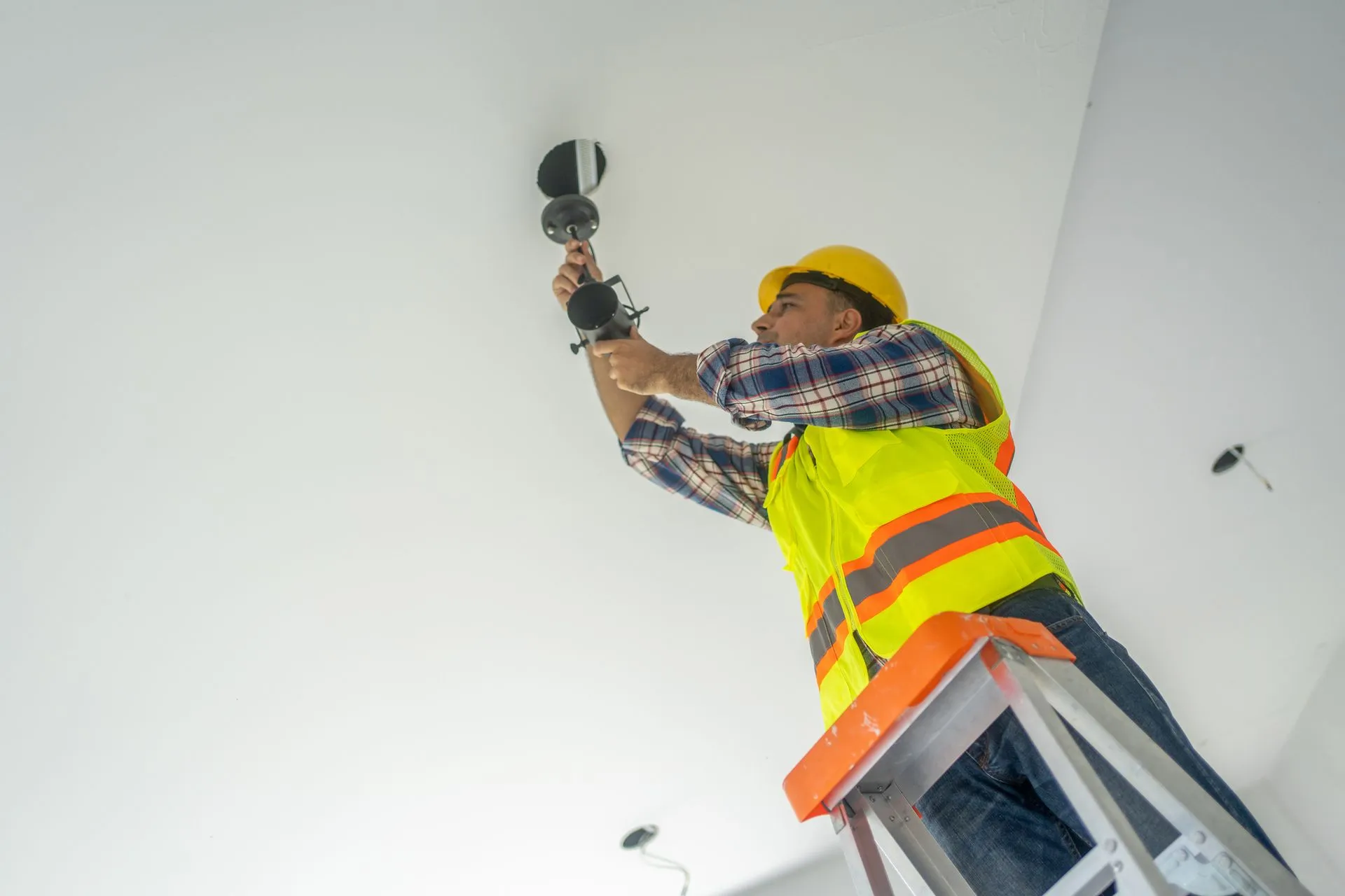 Electrician installing ceiling lamp