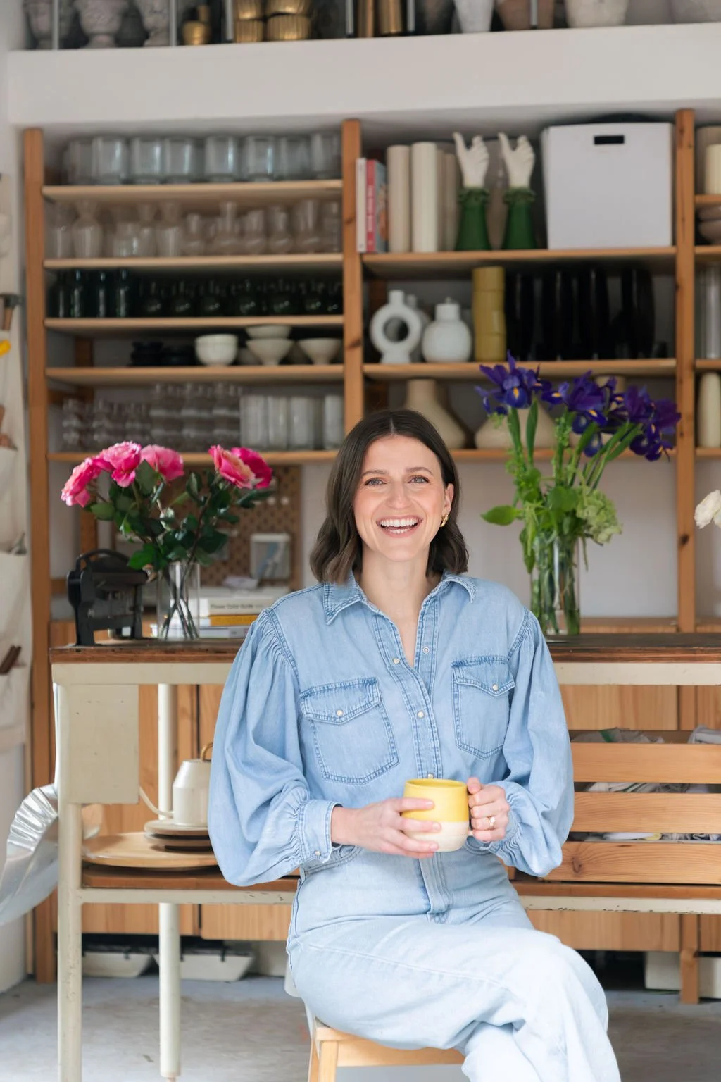 A woman holding a mug of coffee in a flower shop