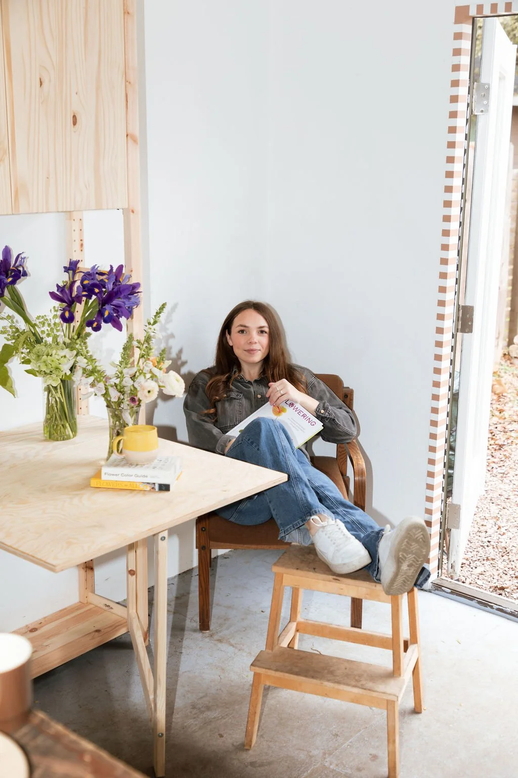 Florist sitting with her flowers at a wooden table