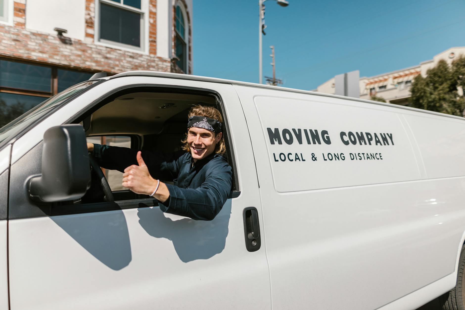 Smiling mover giving thumbs up from moving van