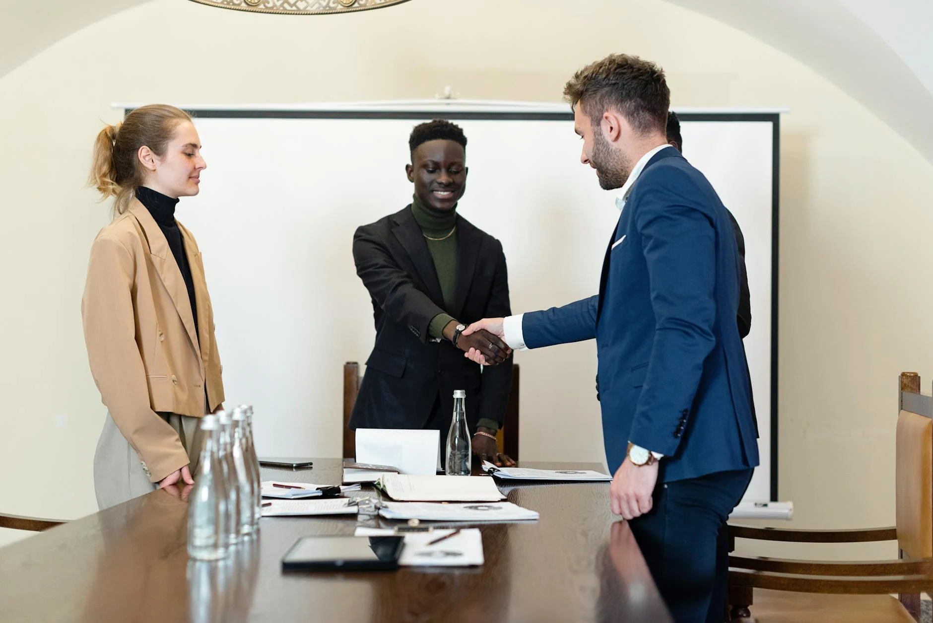 Diverse professionals in a meeting room, shaking hands
