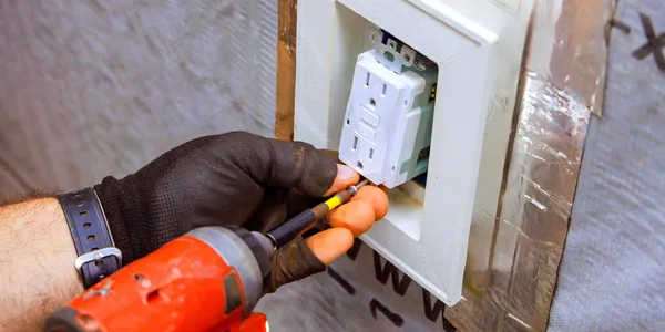 A person installs an electrical outlet using a power screwdriver