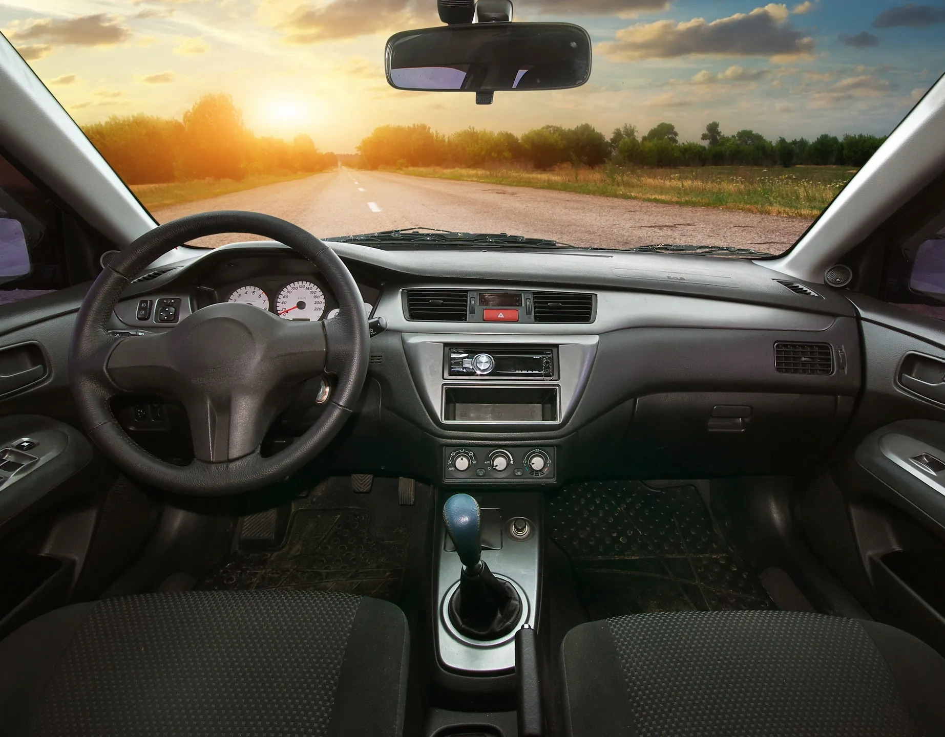 Interior view of a car with a sunset road ahead