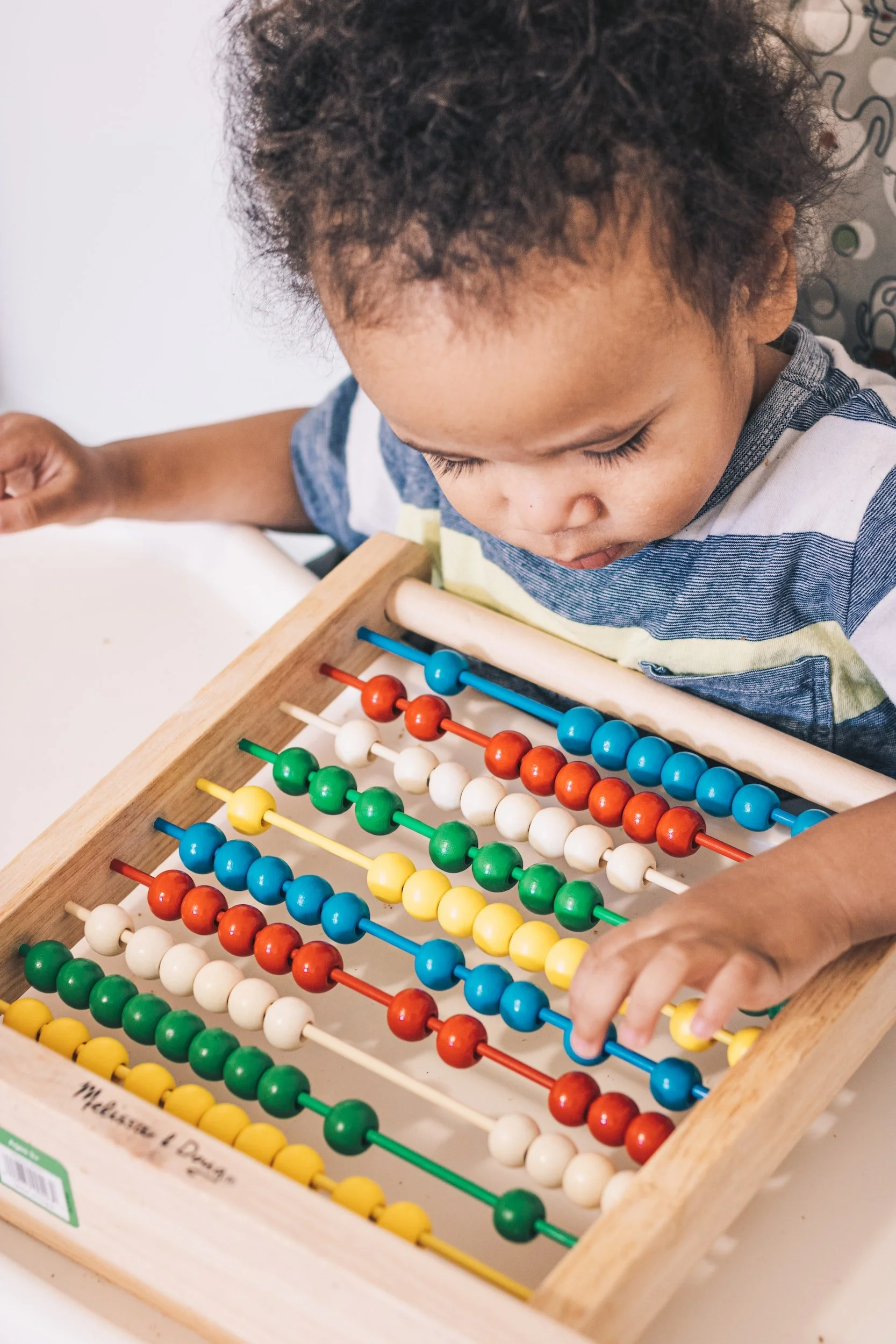 Young child playing with colorful wooden abacus representing early intervention
