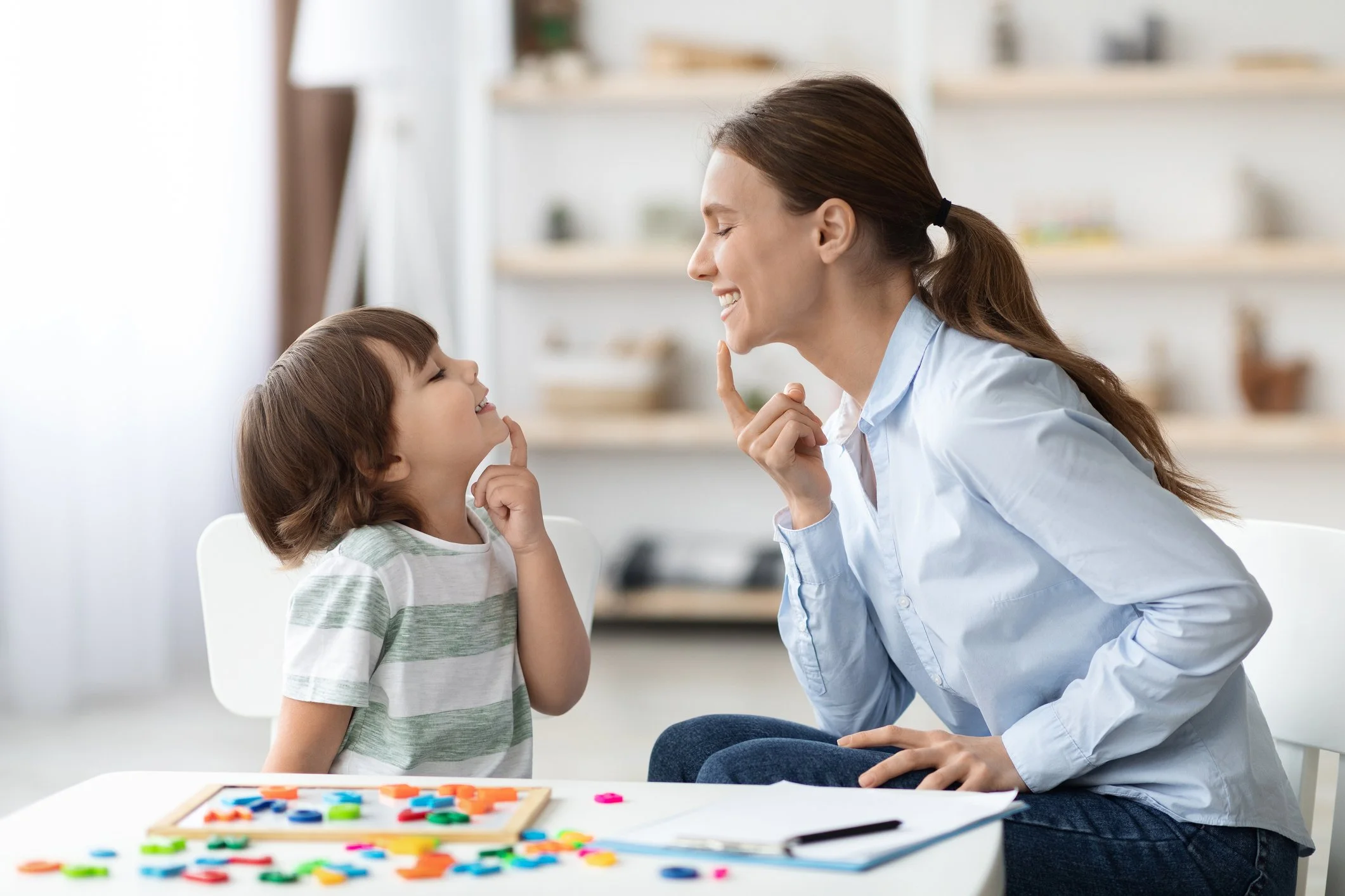 A therapist and child playing with colorful game pieces during a speech therapy session