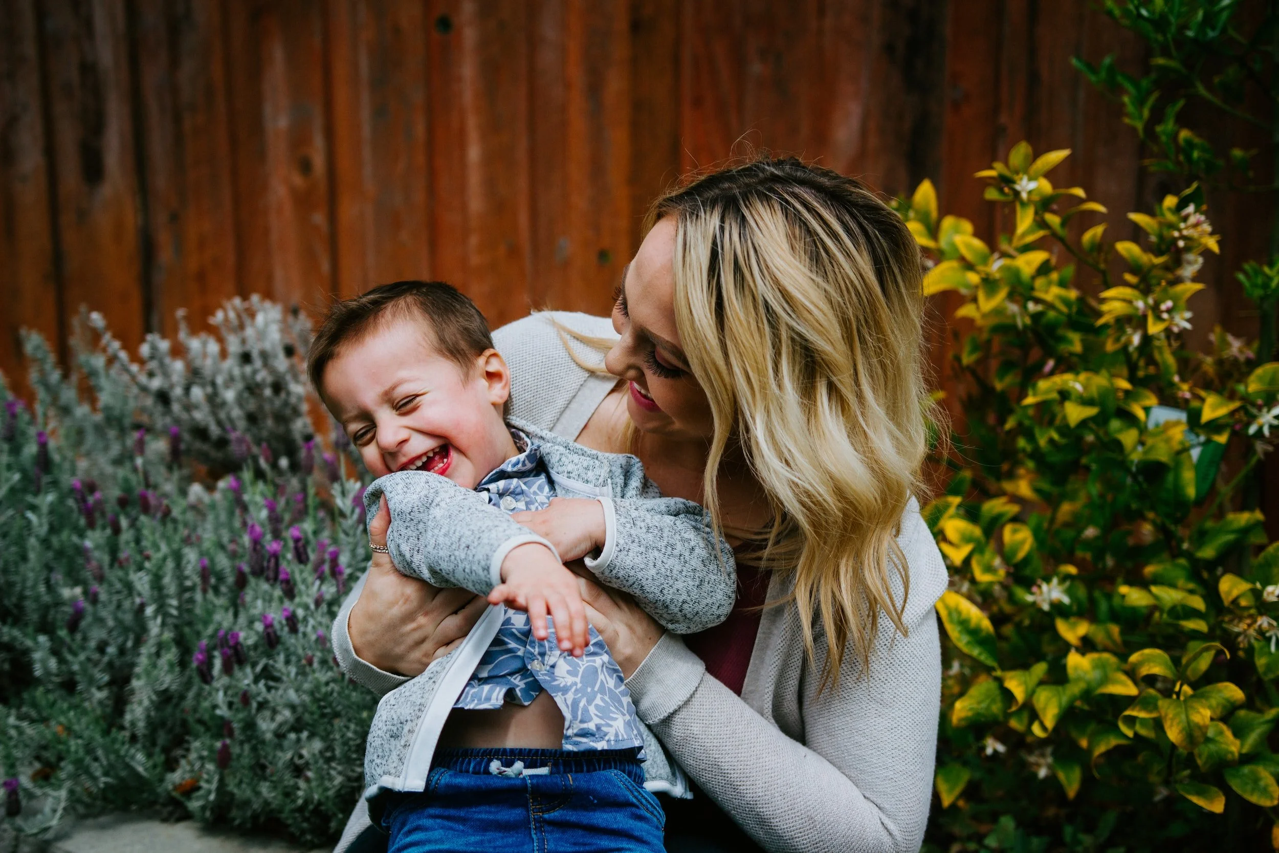 Woman holding a laughing young boy in a garden