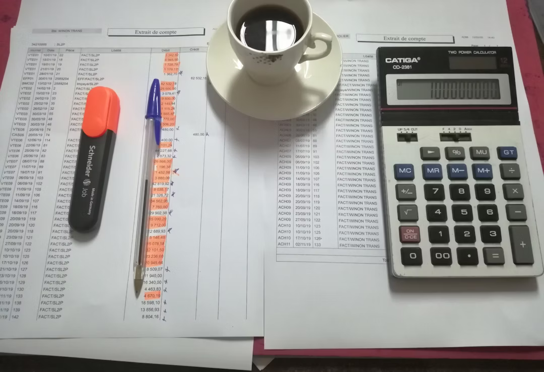 A laptop displaying tax software with financial documents and a calculator on a desk.