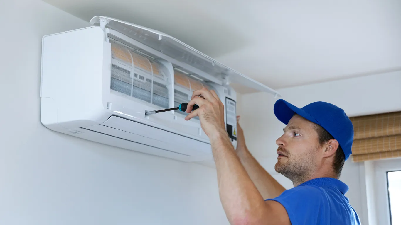 Technician repairing AC with screwdriver