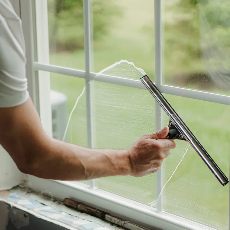 Person cleaning glass windows with squeegee
